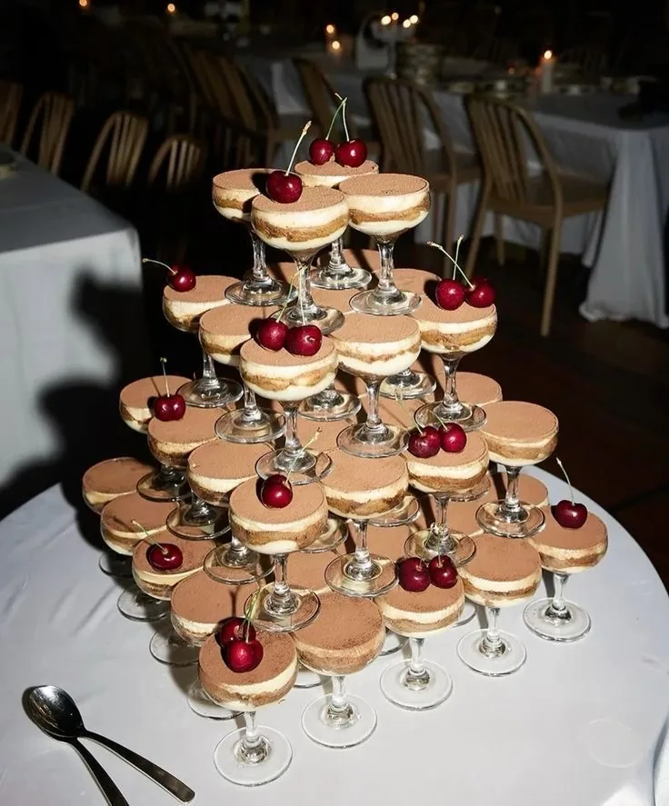 Pyramide de coupes de tiramisu décorées de cerises sur une table de buffet