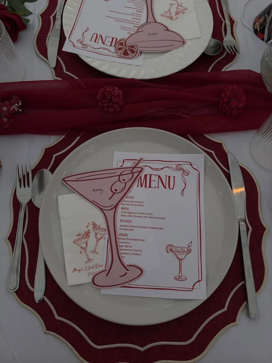Assiette dressée sur un set bordeaux avec menu illustré et carton de place en forme de cocktail